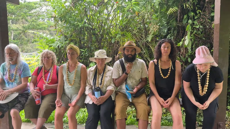 Ra sitting with retreat students on a bench under a rainforest pavilion