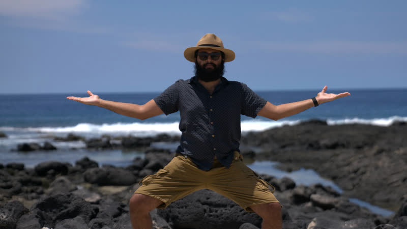 Ra with arms open on black lava rock by the ocean